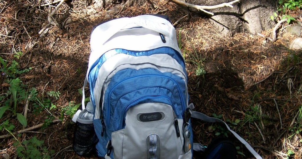 A tan internal-frame hiking backpack standing upright outdoors on the ground.
